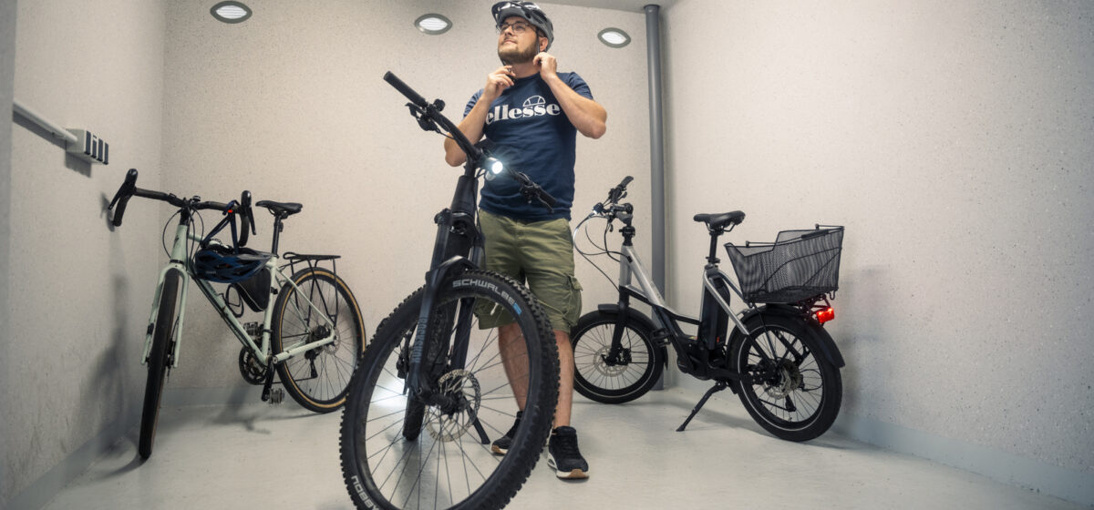 Mann zeiht sich im Fahrradkeller im Hotel Alexa in Bad Mergentheim ein Fahrradhelm an.